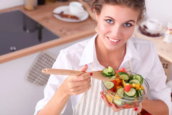 Sorrindo jovem mulher preparando salada na cozinha . — Fotografia de Stock