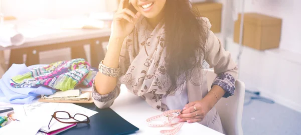 Smiling female fashion designer sitting at office desk — Stock Photo, Image