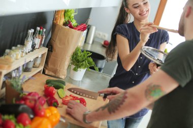 Bir çift evdeki mutfaklarında birlikte yemek pişiriyor.
