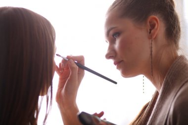 Kadından profesyonel makyaj yapan sanatçı.