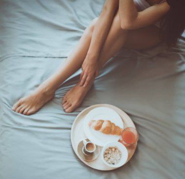 bir bardak süt ile yatakta oturan genç kadın