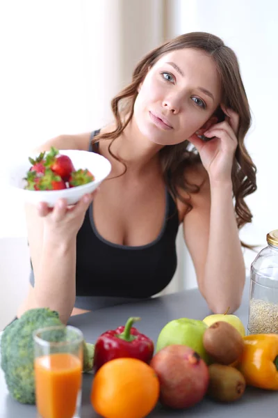 Mädchen sitzt in der Küche auf dem Schreibtisch mit Obst und Gläsern mit Saft. — Stockfoto