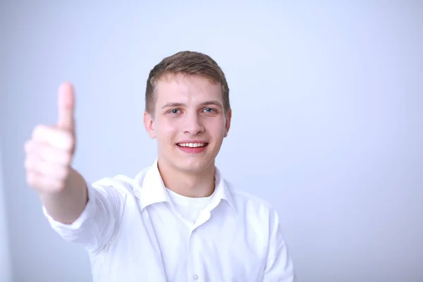 Portret van de jonge man die lacht zittend op een grijze achtergrond. Portret van jonge man — Stockfoto