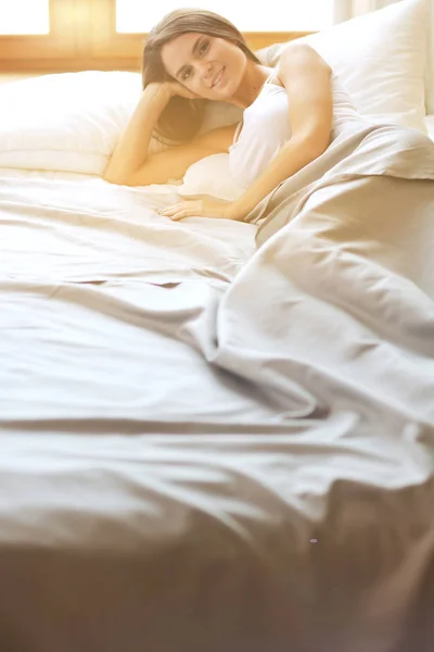 Vacker brunett liggande på sängen hemma — Stockfoto