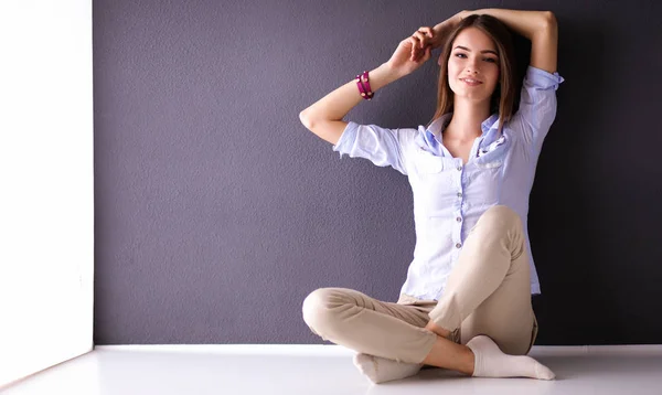 Mujer joven sentada en el suelo cerca de la pared oscura — Foto de Stock