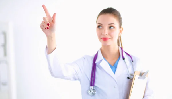 Mulher médico de pé com pasta no hospital e apontando para cima — Fotografia de Stock