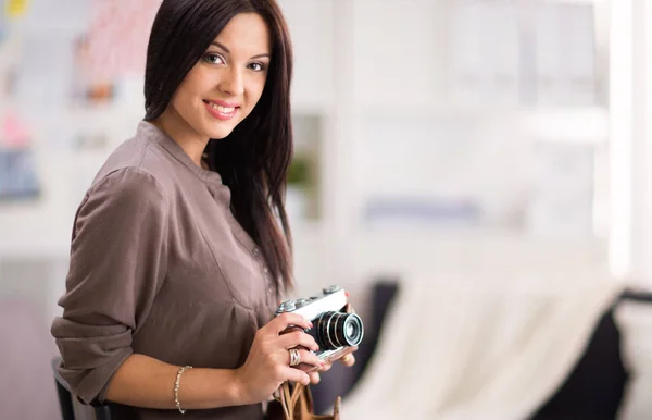 Woman sitting on a sofa in her house with camera — Stock Photo, Image