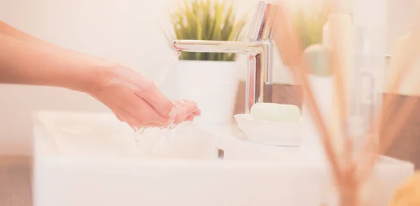 Jonge vrouw wassen haar gezicht met schoon water in badkamer — Stockfoto