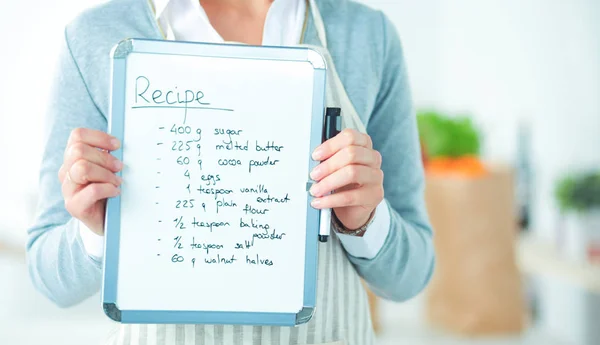 Kvinna i köket hemma, stående nära skrivbord med mapp — Stockfoto