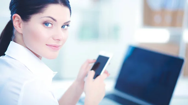 İş kadını ofiste oturan akıllı telefonuyla mesaj gönderiyor. — Stok fotoğraf
