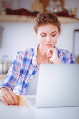 Gülümseyen kadın mutfakta bilgisayar ve kredi kartı kullanarak alışveriş online. Gülümseyen kadın