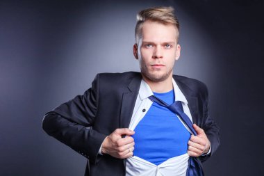 Genç işadamı hareket ve bir süper kahraman gibi gömleğini, yırtılma gri arka plan üzerinde izole. Genç işadamı