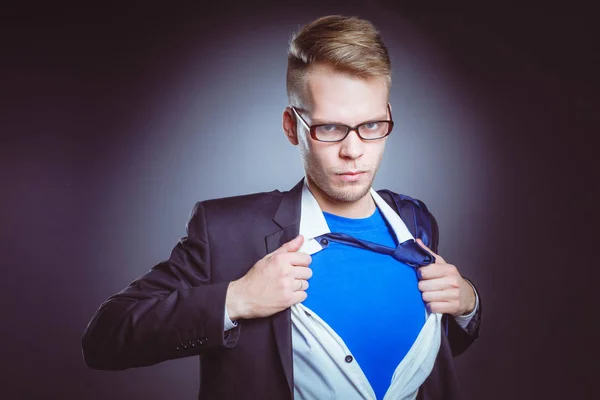 Jonge zakenman handelt zoals een super held en scheuren zijn overhemd, geïsoleerd op een grijze achtergrond. Jonge zakenman — Stockfoto