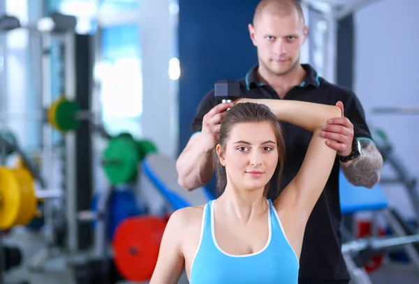 Beautiful woman at the gym exercising with her trainer. Beautiful woman. Gym