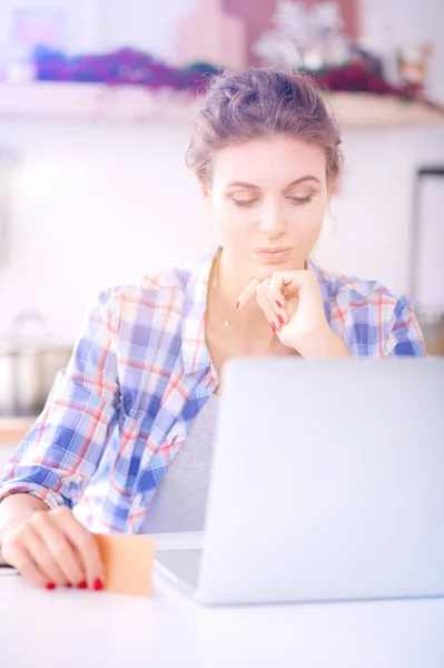 Mulher sorrindo compras on-line usando computador e cartão de crédito na cozinha. Mulher sorridente — Fotografia de Stock