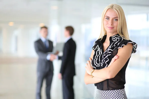 Portrait of young businesswoman in office with colleagues in the background . — Stock Photo, Image