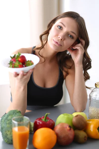 Chica sentada en la cocina en el escritorio con frutas y vasos con jugo . — Foto de Stock