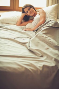 Evdeki yatakta uzanmış güzel esmer