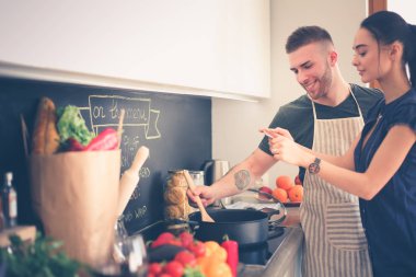 Bir çift evdeki mutfaklarında birlikte yemek pişiriyor.