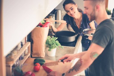 Bir çift evdeki mutfaklarında birlikte yemek pişiriyor.