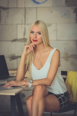 Moda tasarımcıları stüdyoda çalışıyor. Masanın üzerinde oturuyorlar..