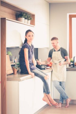 Bir çift evdeki mutfaklarında birlikte yemek pişiriyor.