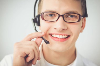 Gri arka plan üzerinde oturan gülümseyen genç adam portresi. Genç adam portresi