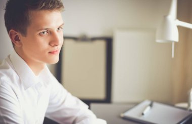 Genç iş adamı ayakta ofisinde çalışıyor. Genç iş adamı