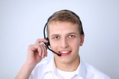 Gri arka plan üzerinde oturan gülümseyen genç adam portresi. Genç adam portresi