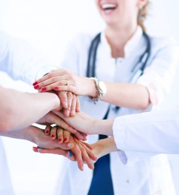 Doktorlar ve hemşireler tıbbi bir ekipte el ele tutuşuyorlar. 