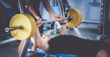 Genç adam eğitmen ile spor salonunda halter kaldırma