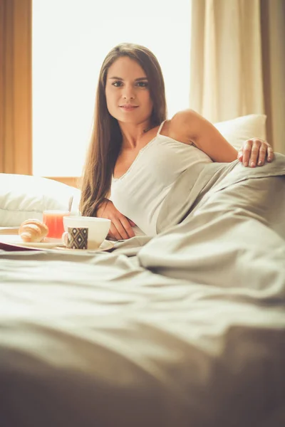 年轻女子坐在床上与一杯牛奶 — 图库照片