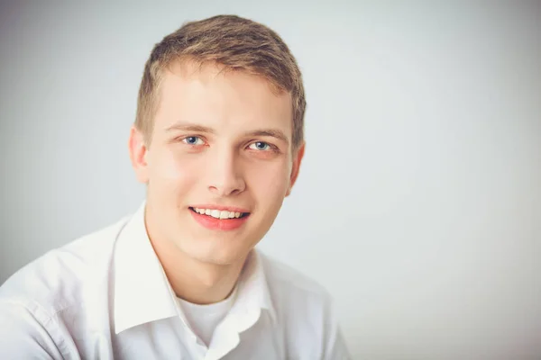 Portret van de jonge man die lacht zittend op een grijze achtergrond. Portret van jonge man — Stockfoto