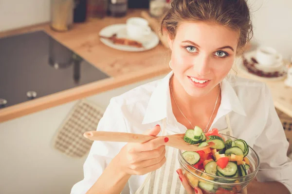 Uśmiechnięta młoda kobieta przygotowanie sałatka w kuchni. — Zdjęcie stockowe