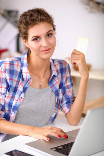 Lachende vrouw online winkelen met behulp van computer- en credit card in keuken. Lachende vrouw — Stockfoto