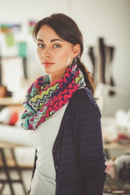 Güzel genç moda tasarımcısı stüdyoda duruyor. .