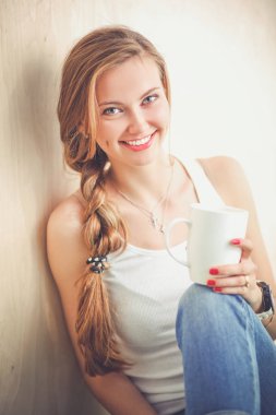 Katta oturan ve bir fincan tutan güzel bir kadın. Güzel kadın