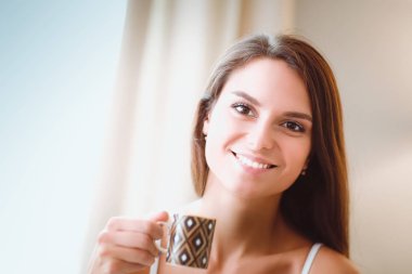 bir bardak süt ile yatakta oturan genç kadın