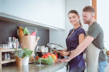 Bir çift evdeki mutfaklarında birlikte yemek pişiriyor.