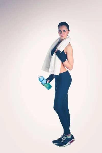 白い背景で隔離のタオルで立っている若い美しいスポーツ女性. — ストック写真