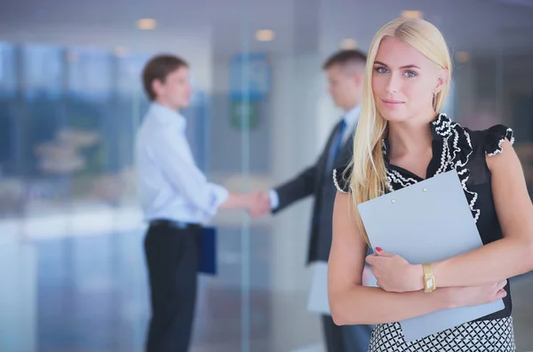 Portrait of young businesswoman in office with colleagues in the background . — Stock Photo, Image