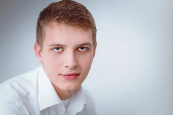 Portret van de jonge man die lacht zittend op een grijze achtergrond. Portret van jonge man — Stockfoto