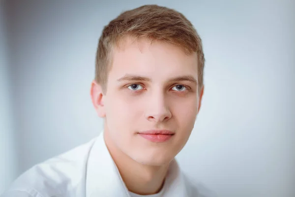 Retrato de um jovem sorrindo sentado sobre fundo cinza. Retrato do jovem — Fotografia de Stock