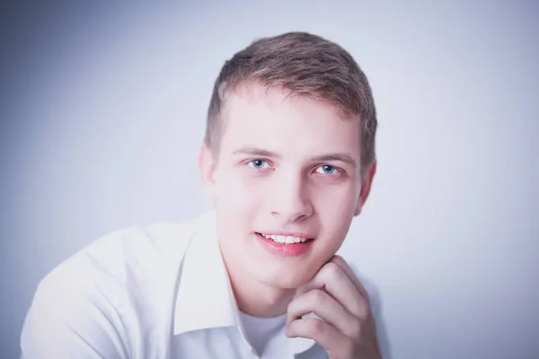 Ritratto di giovane uomo sorridente seduto su sfondo grigio. Ritratto di giovane — Foto Stock