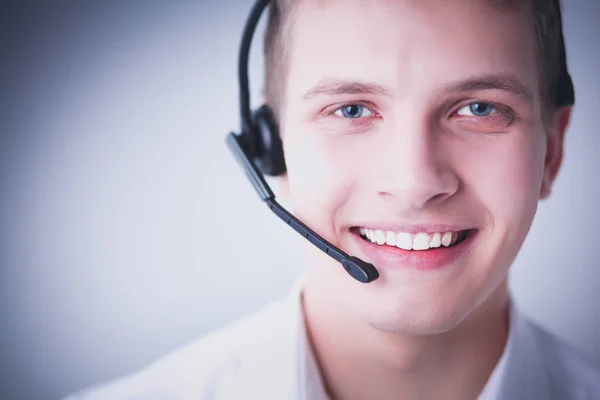 Retrato de un joven sonriendo sentado sobre un fondo gris. Retrato del joven —  Fotos de Stock