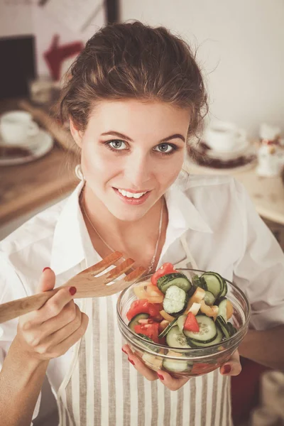 부엌에서 샐러드를 준비 하는 젊은 여자를 웃 고. — 스톡 사진