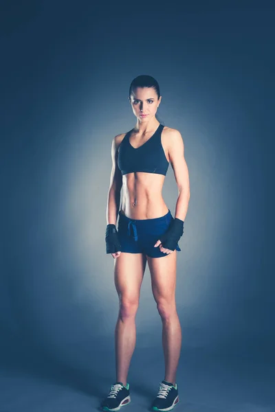 Muscolare giovane donna in posa in abbigliamento sportivo contro sfondo nero . — Foto Stock