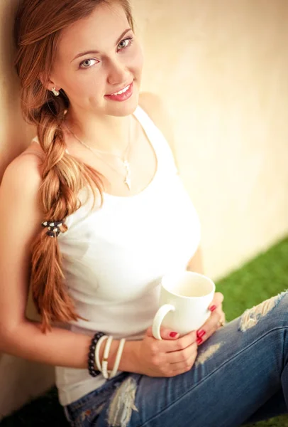 Beautiful woman sitting on the floor and holding a cup. Beautiful woman — Stock Photo, Image