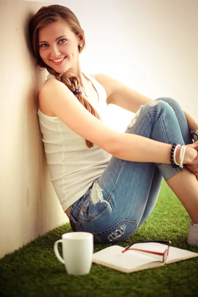 Hermosa mujer sentada en el suelo y sosteniendo una taza. Hermosa mujer —  Fotos de Stock