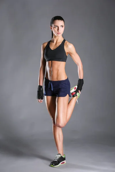 Musculosa joven posando en ropa deportiva sobre fondo negro . — Foto de Stock